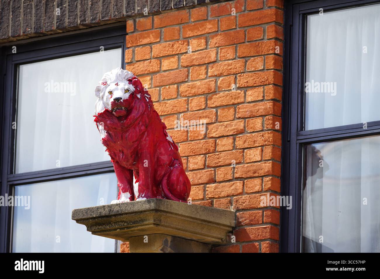 Statua del Leone dipinta di rosso e bianco fuori dall'edificio in mattoni. Salisbury, Inghilterra Foto Stock
