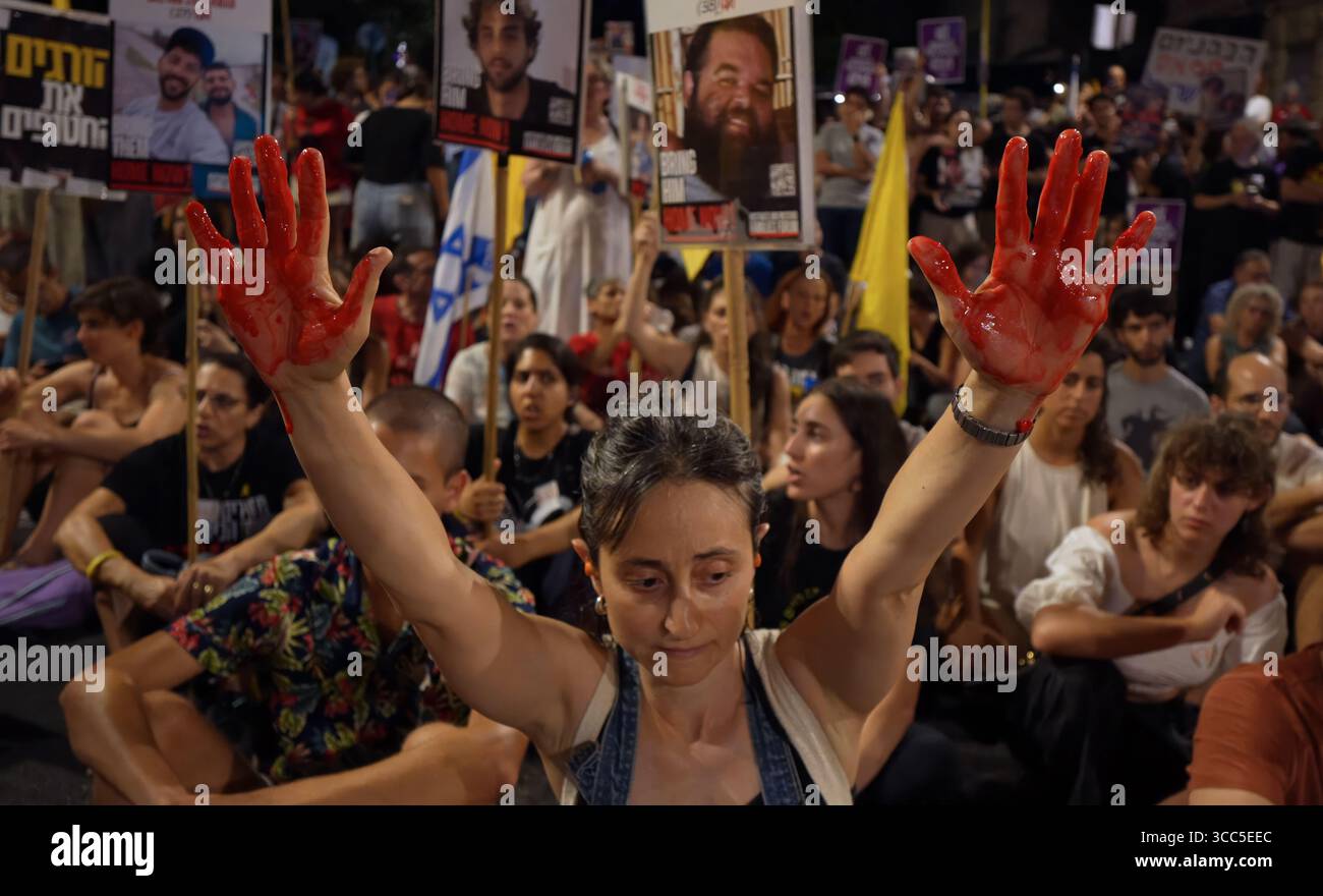 GERUSALEMME - 9 AGOSTO: Un manifestante tiene le mani dipinte di rosso per simboleggiare le vittime di guerra come manifestanti anti anti-governativi cantano slogan e bloccano una strada vicino alla casa privata del primo ministro Benjamin Netanyahu chiedendo di fermare la guerra e di rilasciare tutti gli ostaggi israeliani in una sola volta il 9 agosto 2025 a Gerusalemme. Il primo ministro Benjamin Netanyahu e il suo gabinetto di sicurezza hanno approvato il controllo completo della città di Gaza, nonostante gli avvertimenti dei funzionari di sicurezza e dei gruppi per i diritti umani che potrebbero mettere in pericolo gli ostaggi di Hamas e i palestinesi che già soffrono di sfollamento e fame. Foto Stock