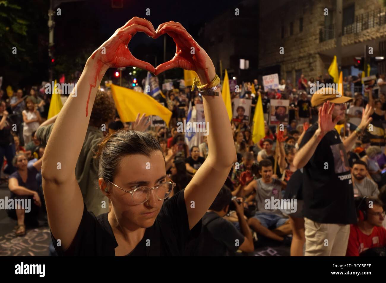 GERUSALEMME - 9 AGOSTO: Un manifestante tiene le mani dipinte di rosso per simboleggiare le vittime di guerra come manifestanti anti anti-governativi cantano slogan e bloccano una strada vicino alla casa privata del primo ministro Benjamin Netanyahu chiedendo di fermare la guerra e di rilasciare tutti gli ostaggi israeliani in una sola volta il 9 agosto 2025 a Gerusalemme. Il primo ministro Benjamin Netanyahu e il suo gabinetto di sicurezza hanno approvato il controllo completo della città di Gaza, nonostante gli avvertimenti dei funzionari di sicurezza e dei gruppi per i diritti umani che potrebbero mettere in pericolo gli ostaggi di Hamas e i palestinesi che già soffrono di sfollamento e fame. Foto Stock