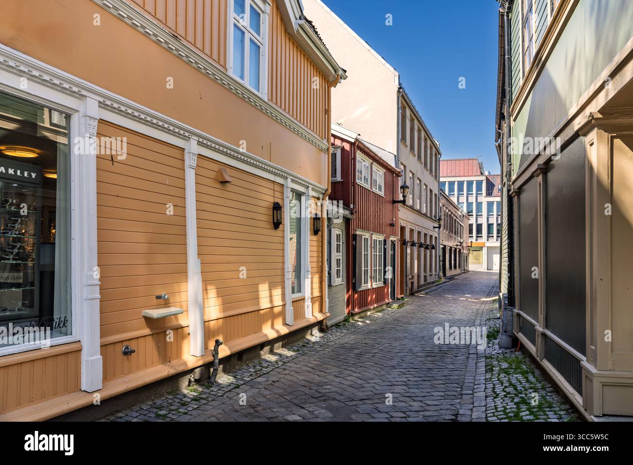 Affascinante stradina fiancheggiata da colorati edifici in legno, caratterizzata da un sentiero acciottolato sotto cieli limpidi, che evoca un'atmosfera nostalgica e accogliente Foto Stock