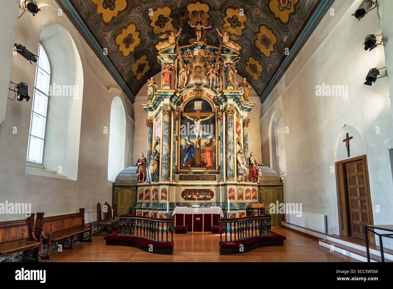 L'interno di una chiesa storica presenta un colorato altare e tradizionali pali di legno, completato da vibranti opere d'arte e intricati elementi decorativi Foto Stock