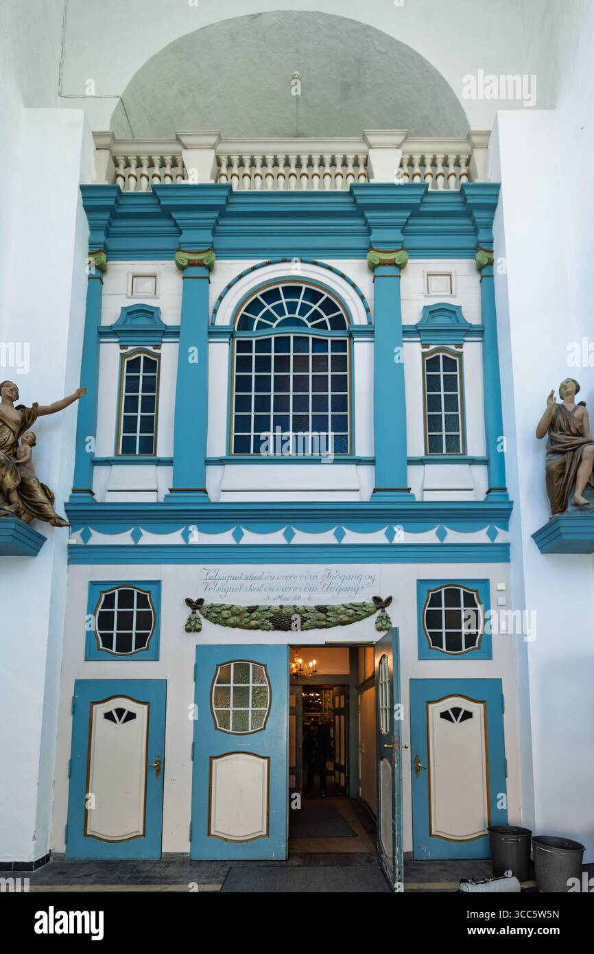 L'esterno di una chiesa storica presenta un colorato altare e tradizionali pali di legno, completato da vibranti opere d'arte e da intricati elementi decorativi Foto Stock