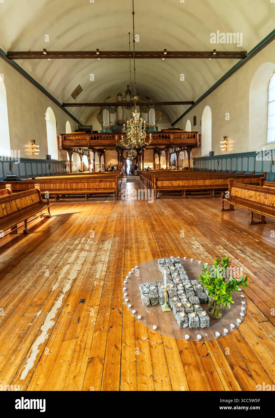 L'interno di una chiesa storica presenta un colorato altare e tradizionali pali di legno, completato da vibranti opere d'arte e intricati elementi decorativi Foto Stock