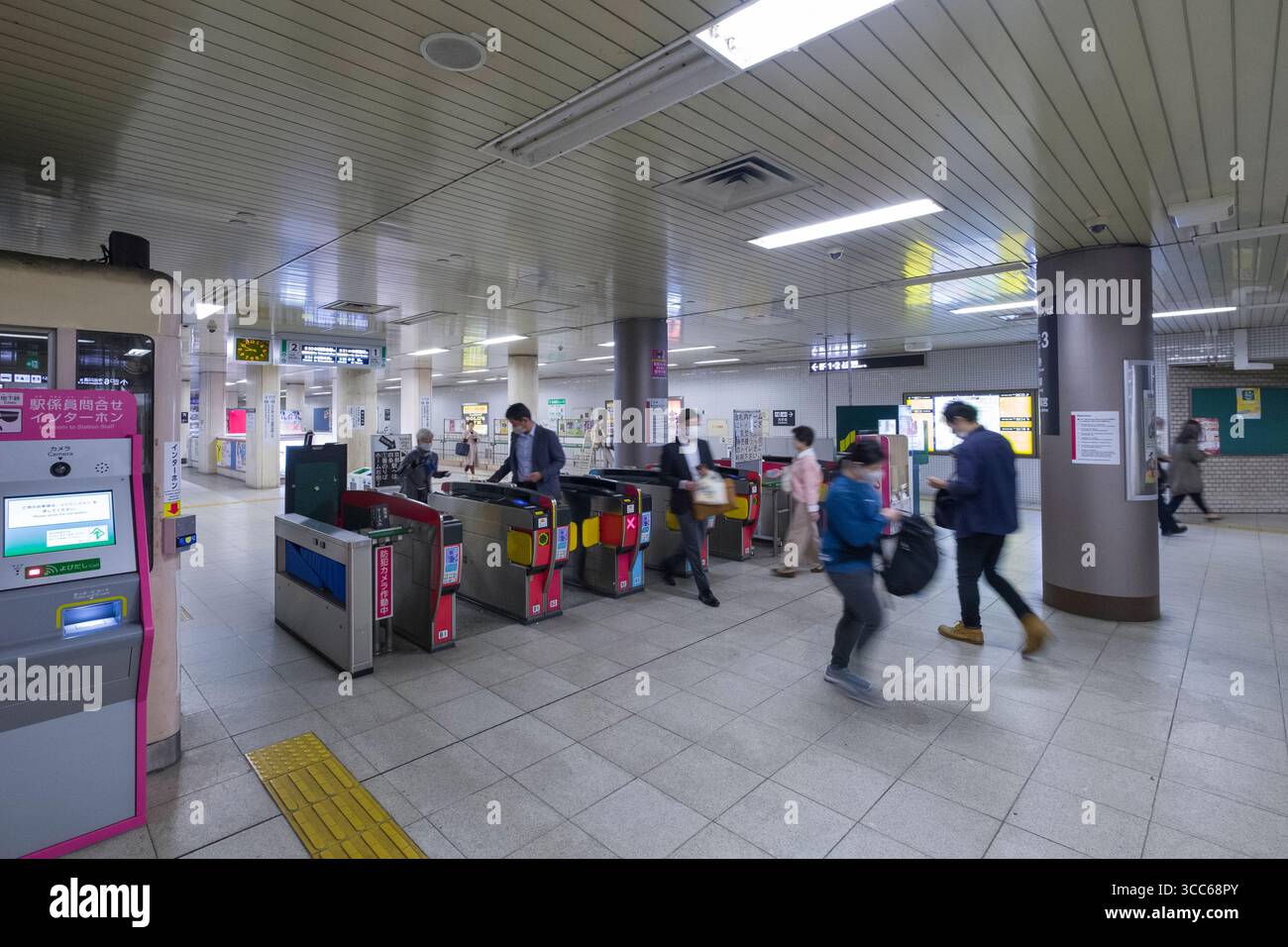 Una stazione della metropolitana attiva piena di pendolari che passano attraverso i tornelli. Le persone si muovono rapidamente, sottolineando la frenetica vita cittadina e urbana Foto Stock