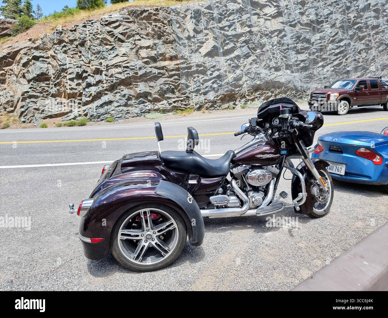 Motocicletta nera Harley-Davidson a 3 ruote, parcheggiata lungo una strada di montagna; CSC California Side Car - Immagine stock catturata con smartphone