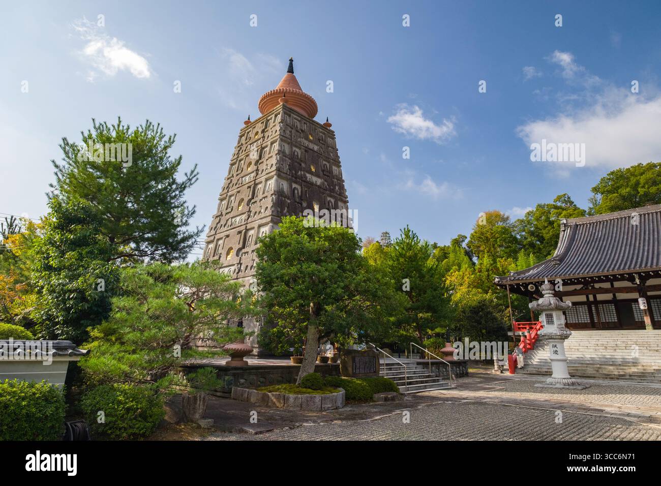 Una serena vista di un antico complesso di templi giapponesi caratterizzato da un'alta pagoda circondata da lussureggiante vegetazione sotto un cielo azzurro. Cattura a tradizionale Foto Stock