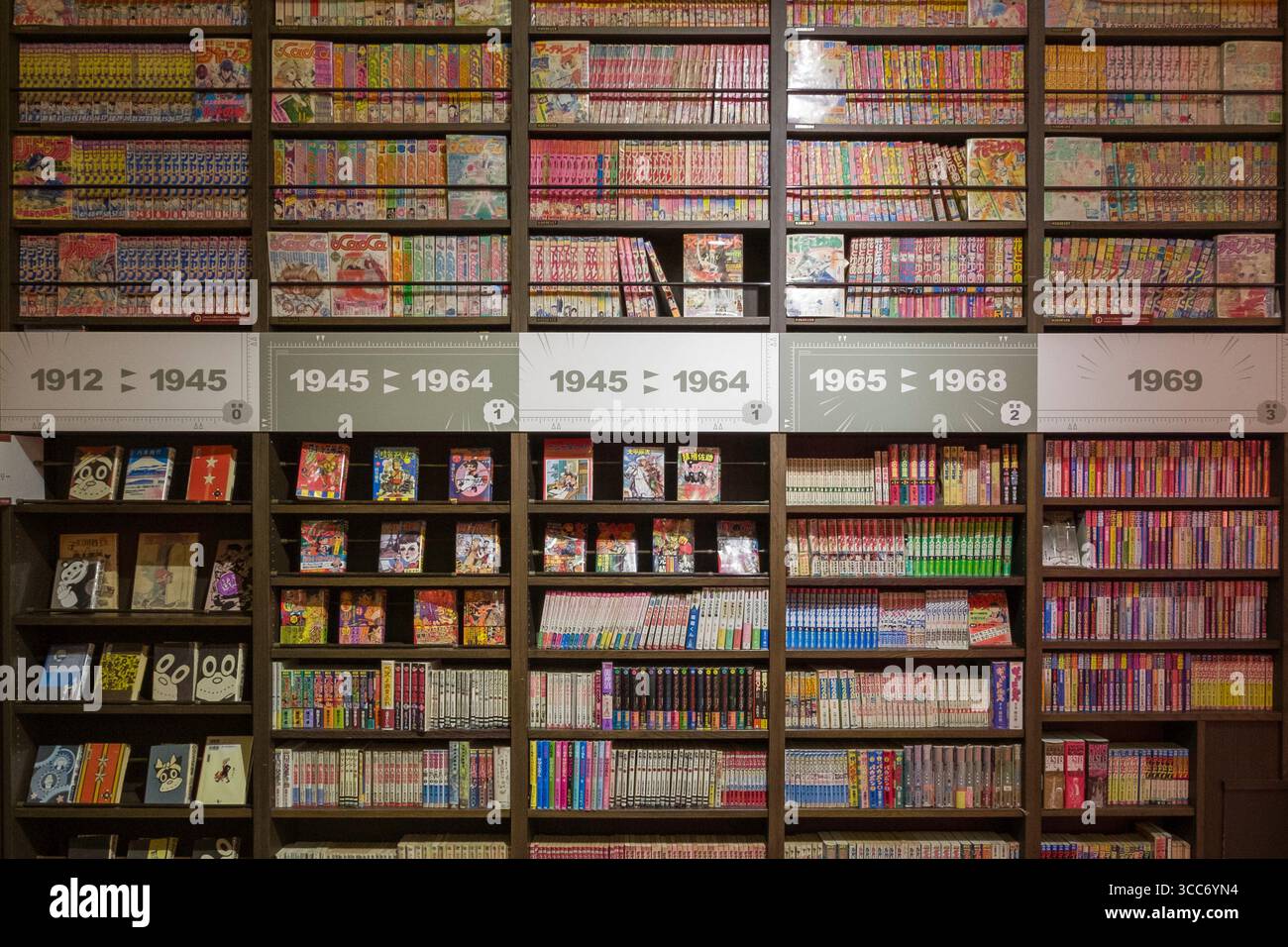 Una vivace esposizione di collezioni di manga organizzate per anno su scaffali in legno in una biblioteca. Le copertine colorate e i libri ordinati creano un invit Foto Stock