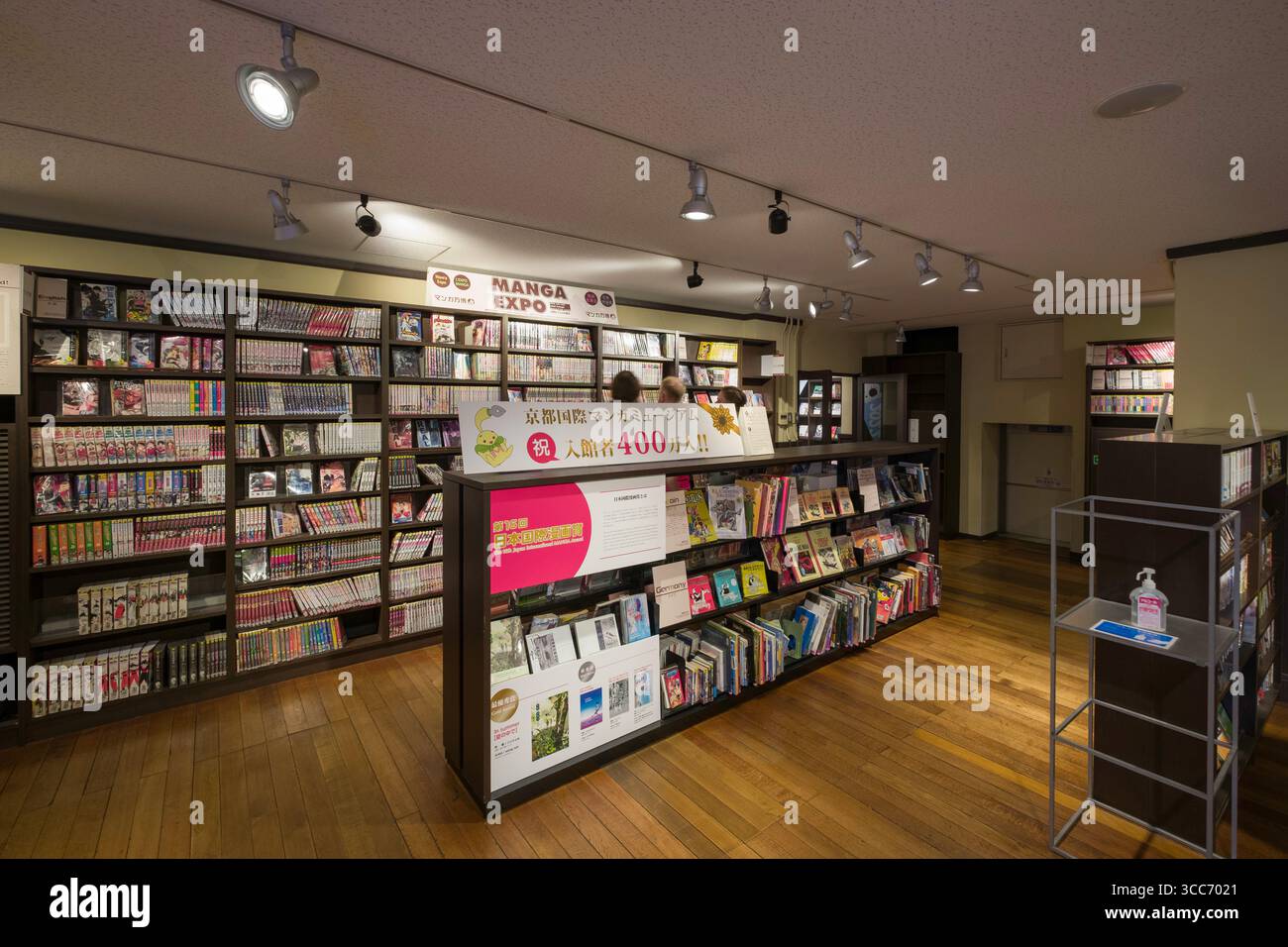 Esplora un'accogliente libreria di manga con scaffali in legno pieni di manga e fumetti. L'illuminazione a soffitto aggiunge un'atmosfera calda, invitando i lettori a farlo Foto Stock