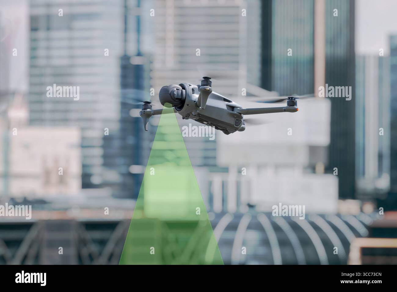 Drone professionale che vola in ambiente urbano con fascio sensore verde visibile per il rilevamento di ostacoli e la navigazione Foto Stock
