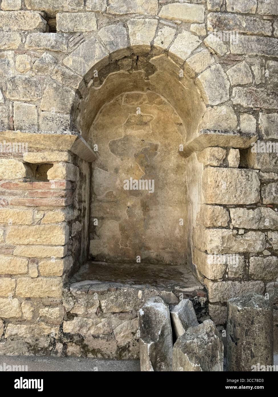 L'antica nicchia di pietra in un muro intemprato rivela la storia architettonica e l'artigianato Foto Stock