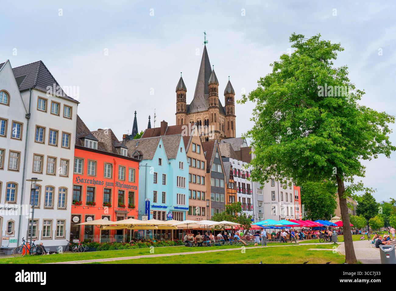 Colonia, Germania - 15 giugno 2025: Edifici colorati sul lungofiume e una cattedrale storica creano una scenografia pittoresca lungo il Reno a Colonia, riflesso Foto Stock