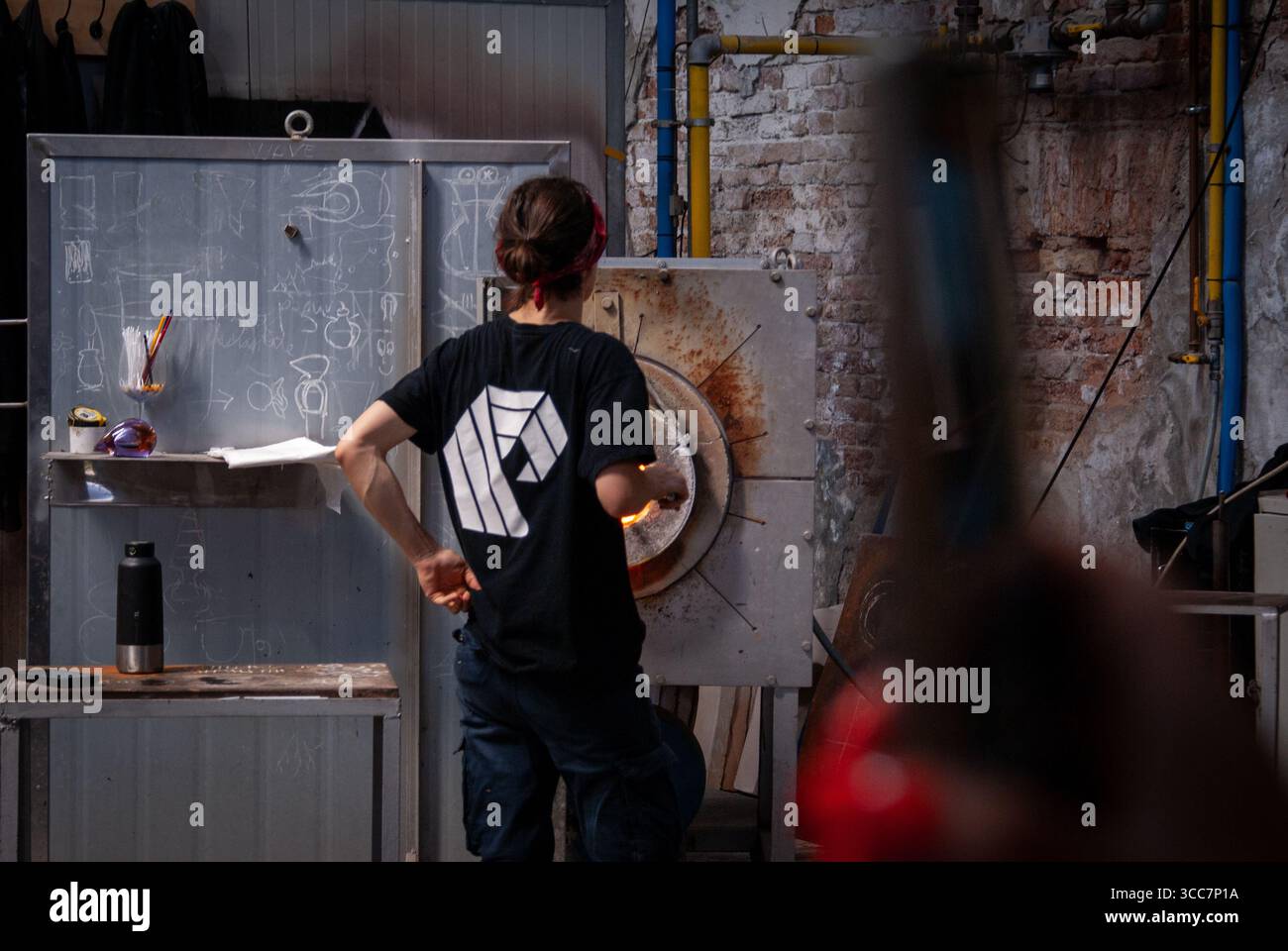 Soffiatore di vetro a Murano, Venezia, fabbrica di vetro Wave Murano, modellatura del vetro in ambiente industriale Foto Stock