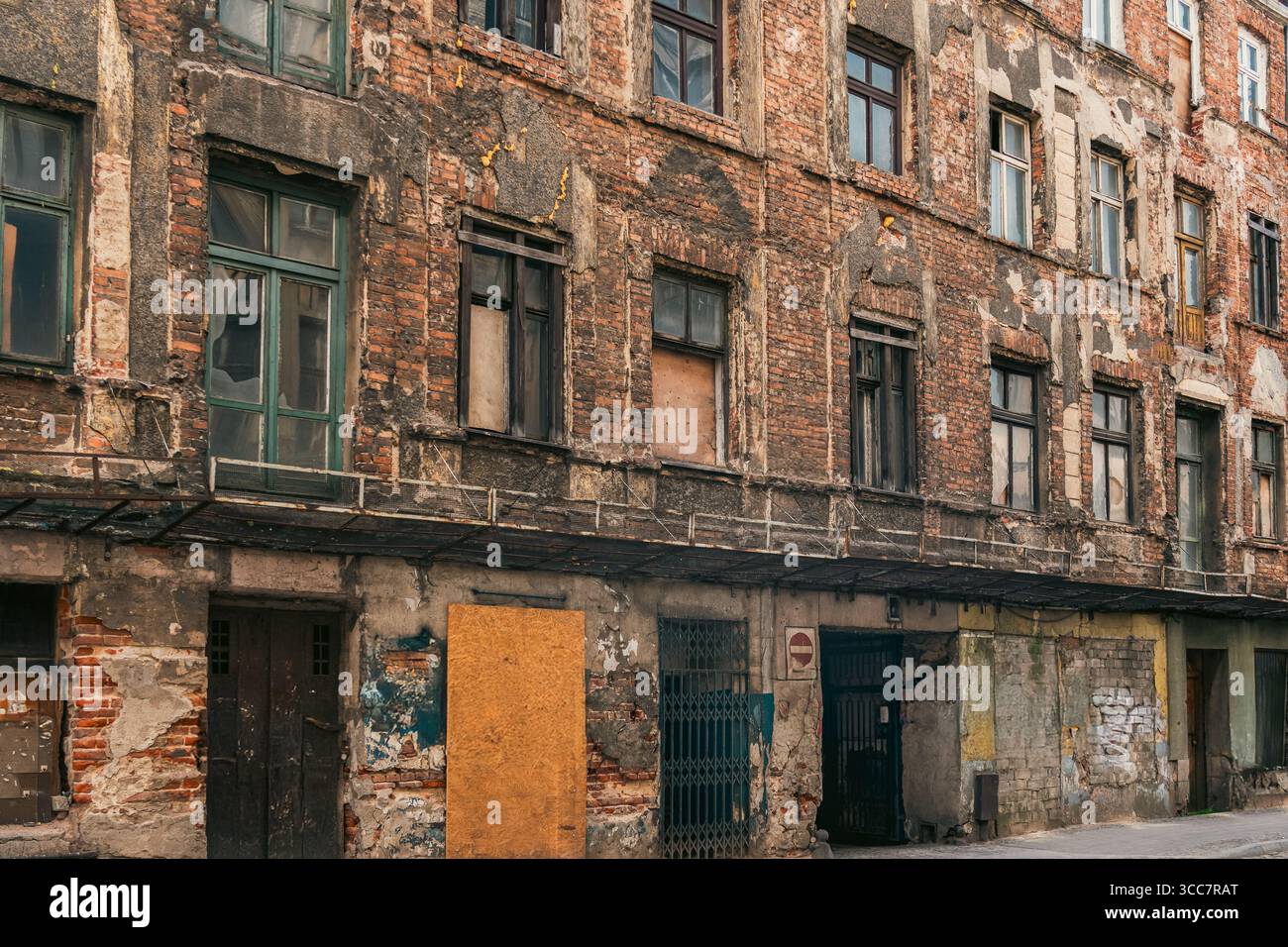 Edificio in mattoni abbandonato concetto di ristrutturazione urbana. La facciata intemprata con finestre a bordo e vernice sbucciante simboleggia l'abbandono, la povertà e il pote Foto Stock