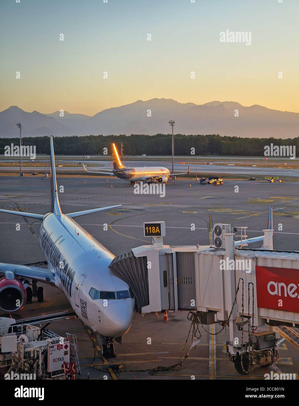 ANTALYA, TURCHIA - 5 LUGLIO 2025 scena aeroportuale di Antalya al tramonto e un aereo attraccato al ponte jet con altri velivoli visibili sull'asfalto. Dista Foto Stock