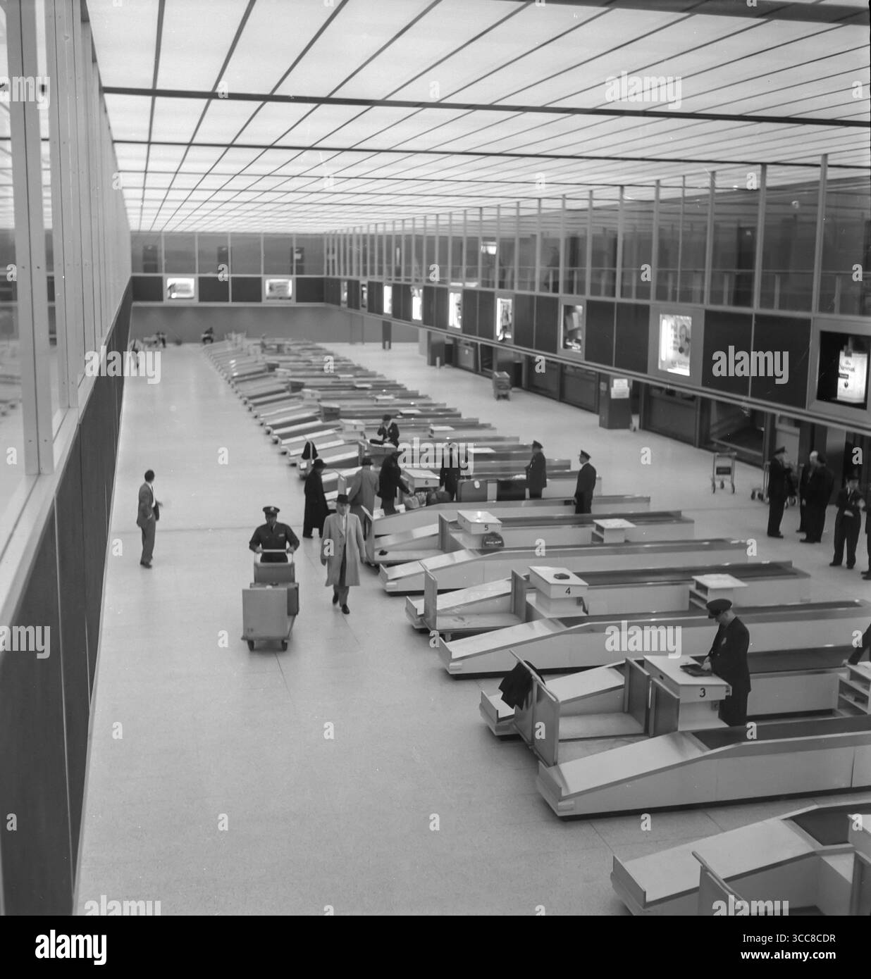 Una fotografia vintage del 1952 in bianco e nero che mostra all'interno dei banchi di check-in del terminal di un grande aeroporto negli Stati Uniti. E' molto silenzioso, con pochissime persone. Foto Stock