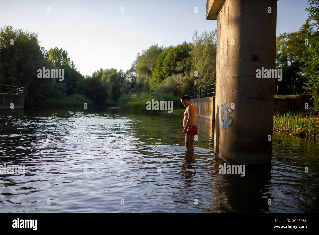 Un uomo si raffredda nel fiume CEA, nella città di Sahagun, nella provincia di Leon. Dopo la seconda ondata di caldo dell'estate, l'AEMET (Agenzia meteorologica statale) ha emesso un avvertimento per temperature estremamente elevate che colpiranno gran parte della Spagna. Foto Stock