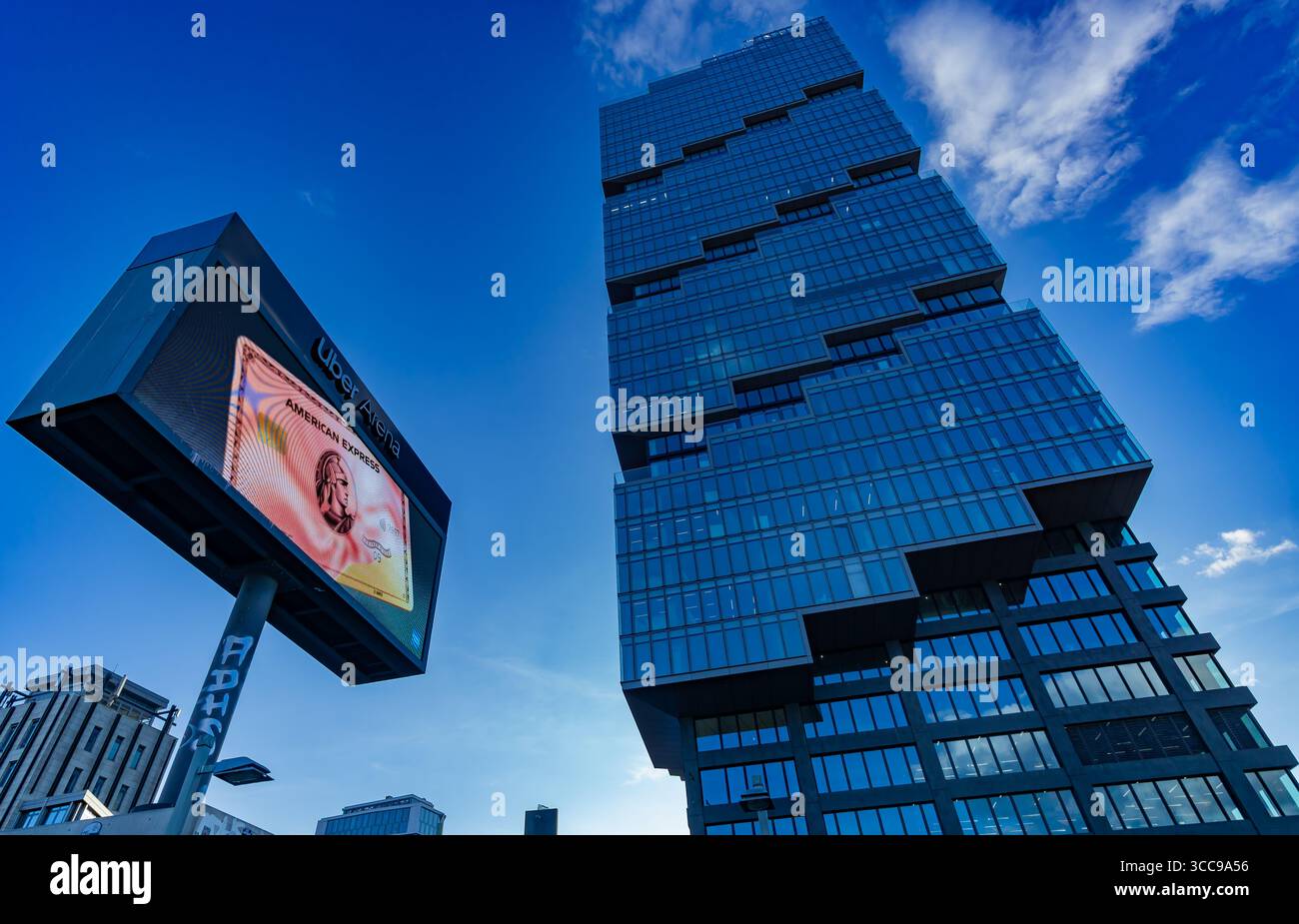 EDGE East Side Berlin Tower (Amazontower) e cartellone pubblicitario a Friedrichshain, vista dall'angolo basso sotto il blu del cielo estivo. Foto Stock