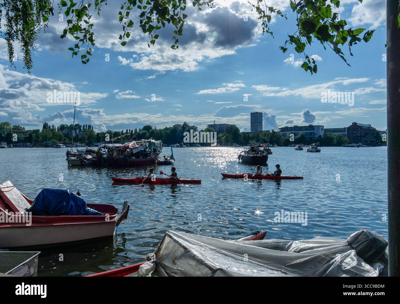 Due canoe rosse con pagaie sul Rummelsburger Bucht a Berlino, catturate dalla riva con la scintillante luce estiva. Foto Stock