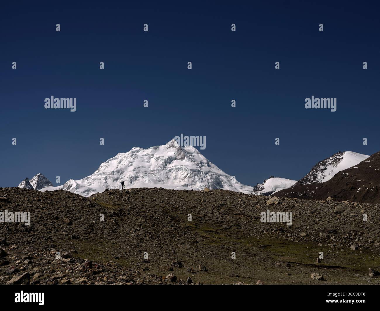 fotografo maschile che cammina sul crinale della montagna con il coleatse sullo sfondo, tibet, cina Foto Stock