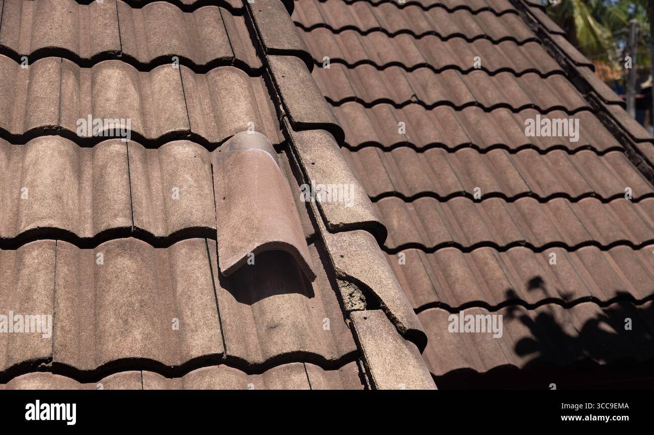 Vecchia tegola danneggiata che necessita di riparazione. Foto Stock