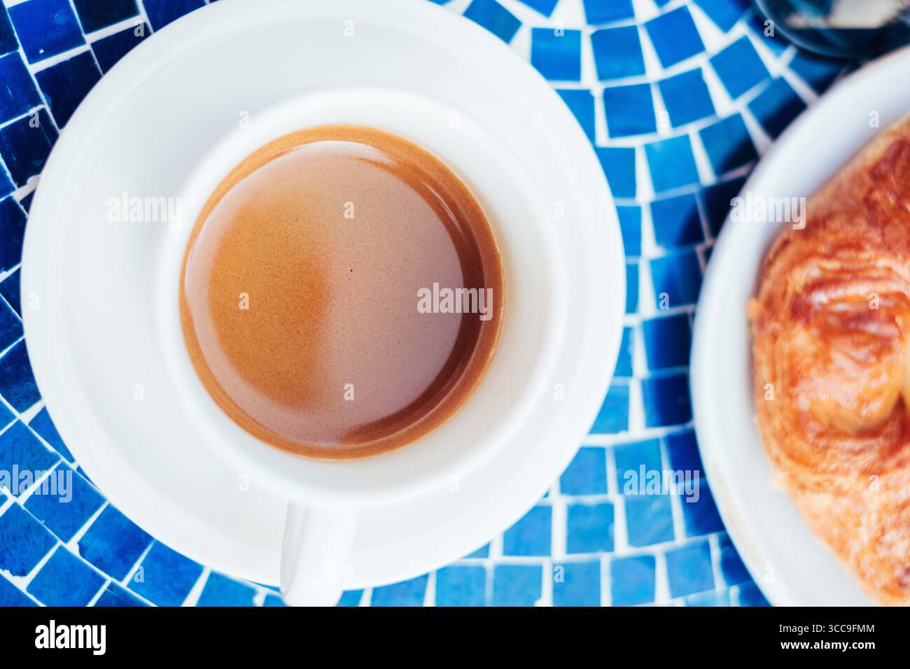 Vista dall'alto dell'espresso e della pasticceria sul tavolo del mosaico blu Foto Stock