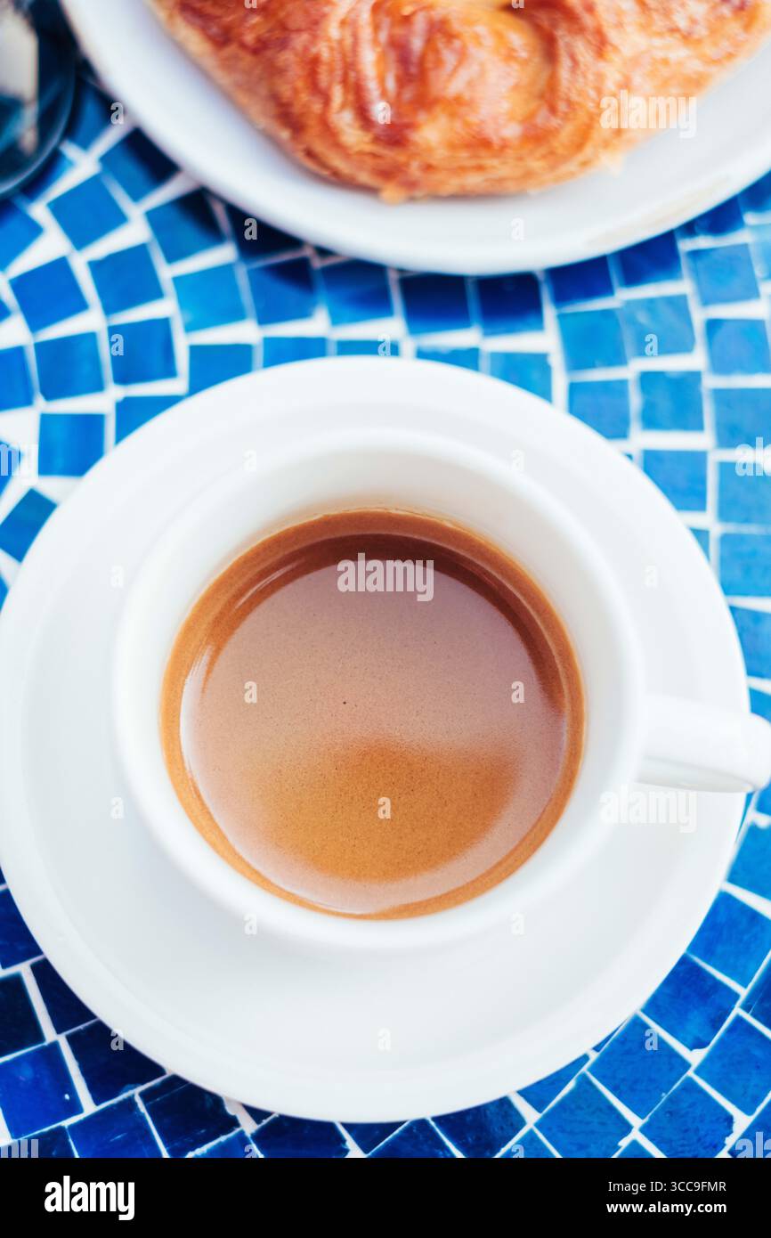 Espresso fresco in tazza bianca su un tavolo con piastrelle blu Foto Stock