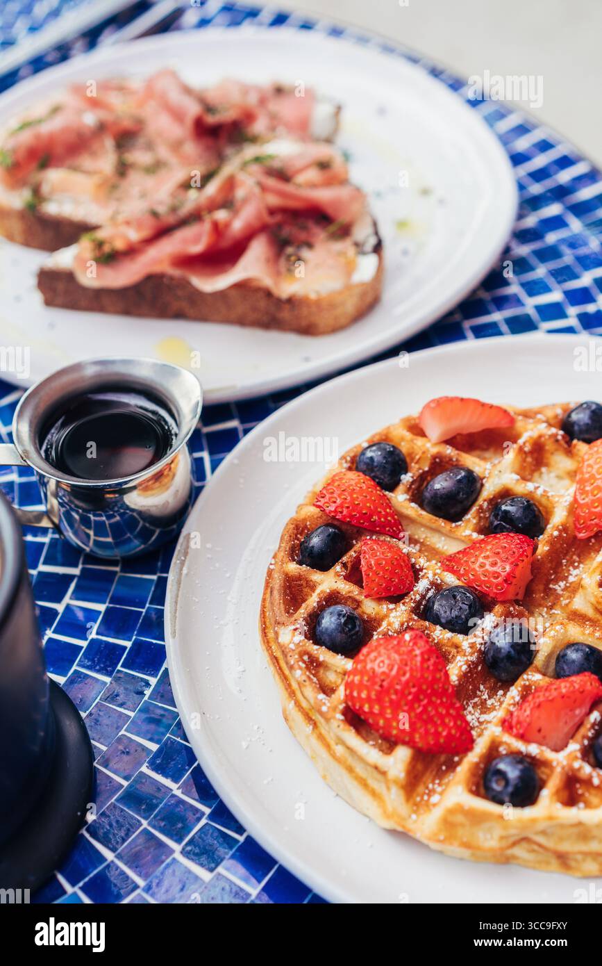 Waffle di frutti di bosco con sciroppo d'acero e toast al prosciutto Foto Stock