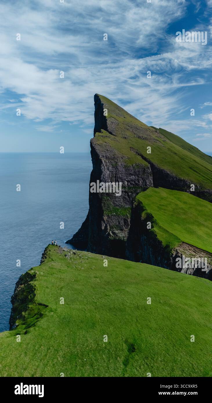 Le torreggianti scogliere di Mylingur si innalzano drammaticamente dalla costa delle Isole Faroe, circondate da una vegetazione lussureggiante e da un vasto oceano. Foto Stock
