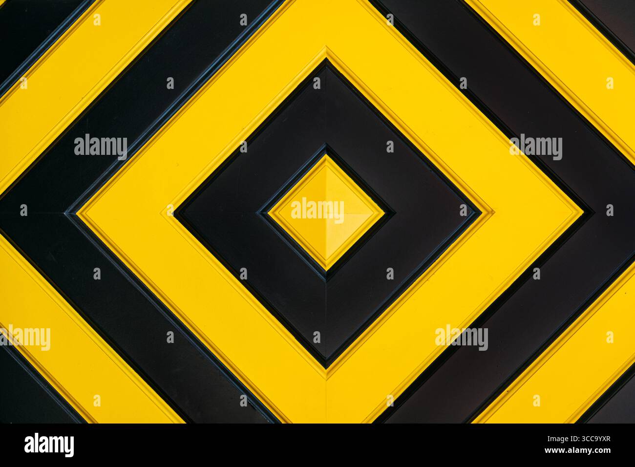 Motivo geometrico caratterizzato da forme di diamante nere e gialle alternate in un layout simmetrico. Astrazione visiva, teoria dei colori, design moderno Foto Stock