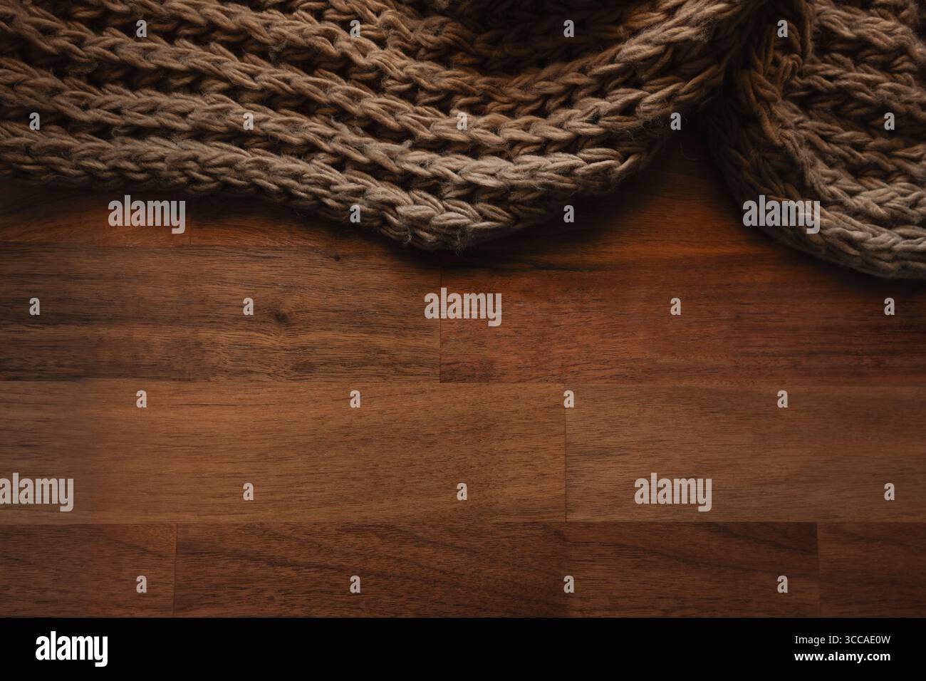 Coperta in lana marrone lavorata a maglia su un tavolo in legno con spazio per copiare Foto Stock