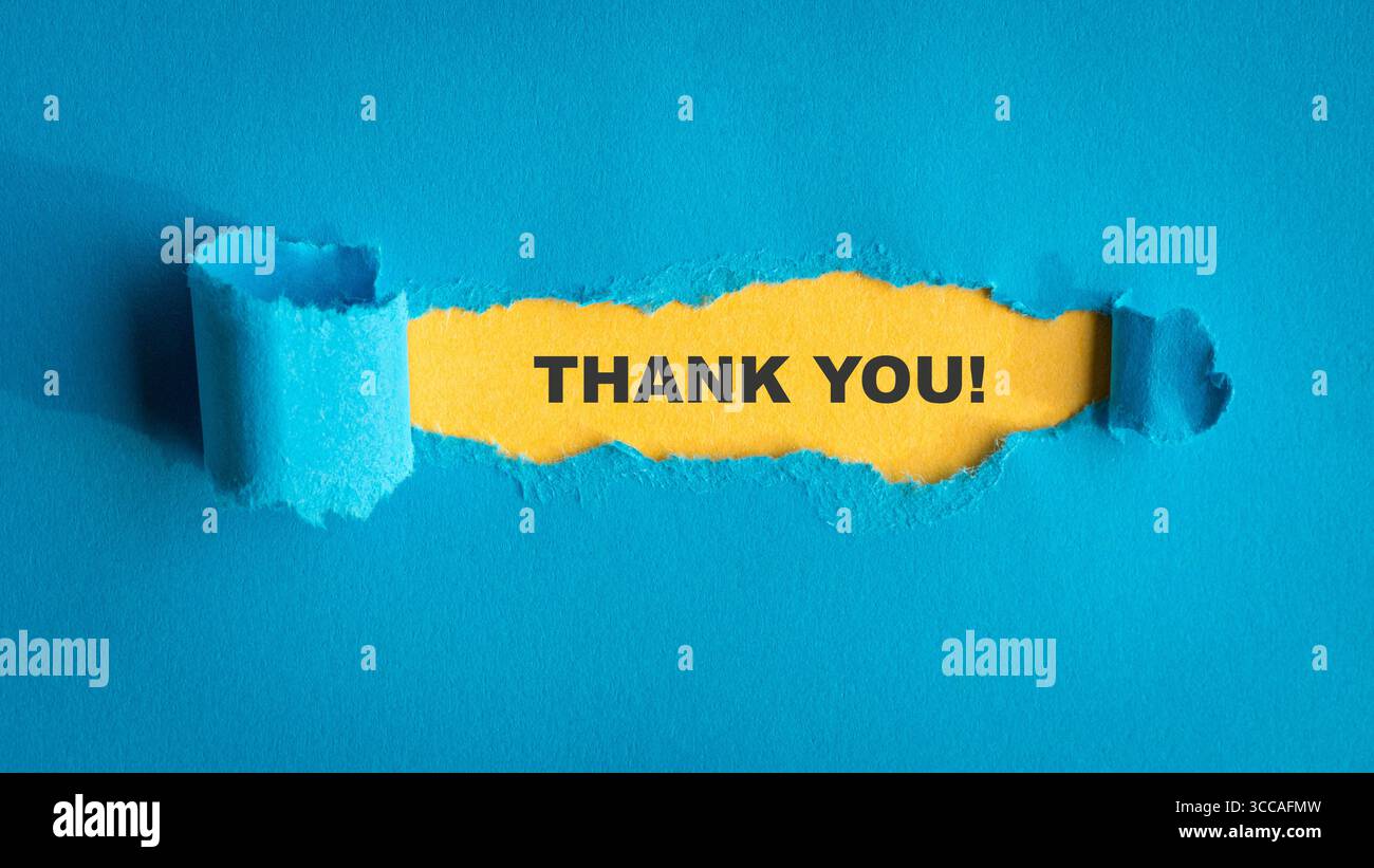 Grazie, messaggio di testo tiposcritto sopra la carta gialla con sopra la carta blu strappata. Foto Stock