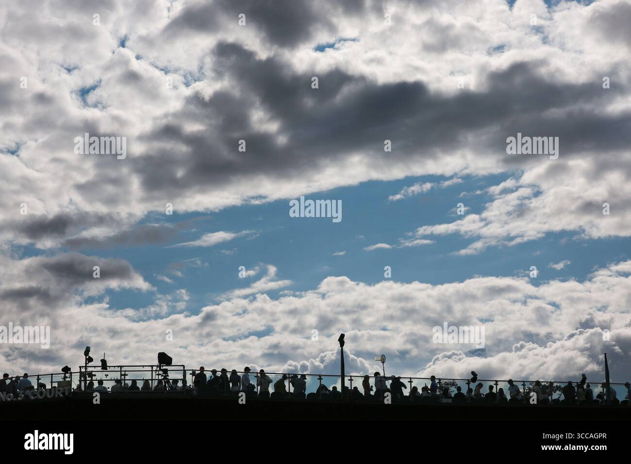 Vista dei tifosi seduti al livello superiore del campo con nuvole scure che incombono sopra ai campionati di Wimbledon del 2025, Londra, Inghilterra, Regno Unito. Foto Stock