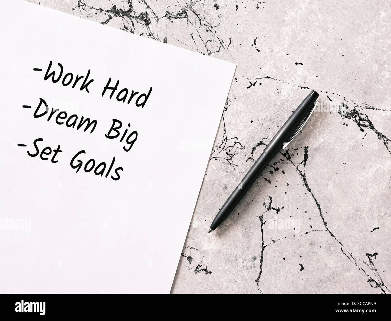 Nota scritta a mano lavora sodo, sogna in grande, fissa obiettivi e una penna su un tavolo di marmo, che rappresenta la motivazione e la pianificazione per il successo Foto Stock