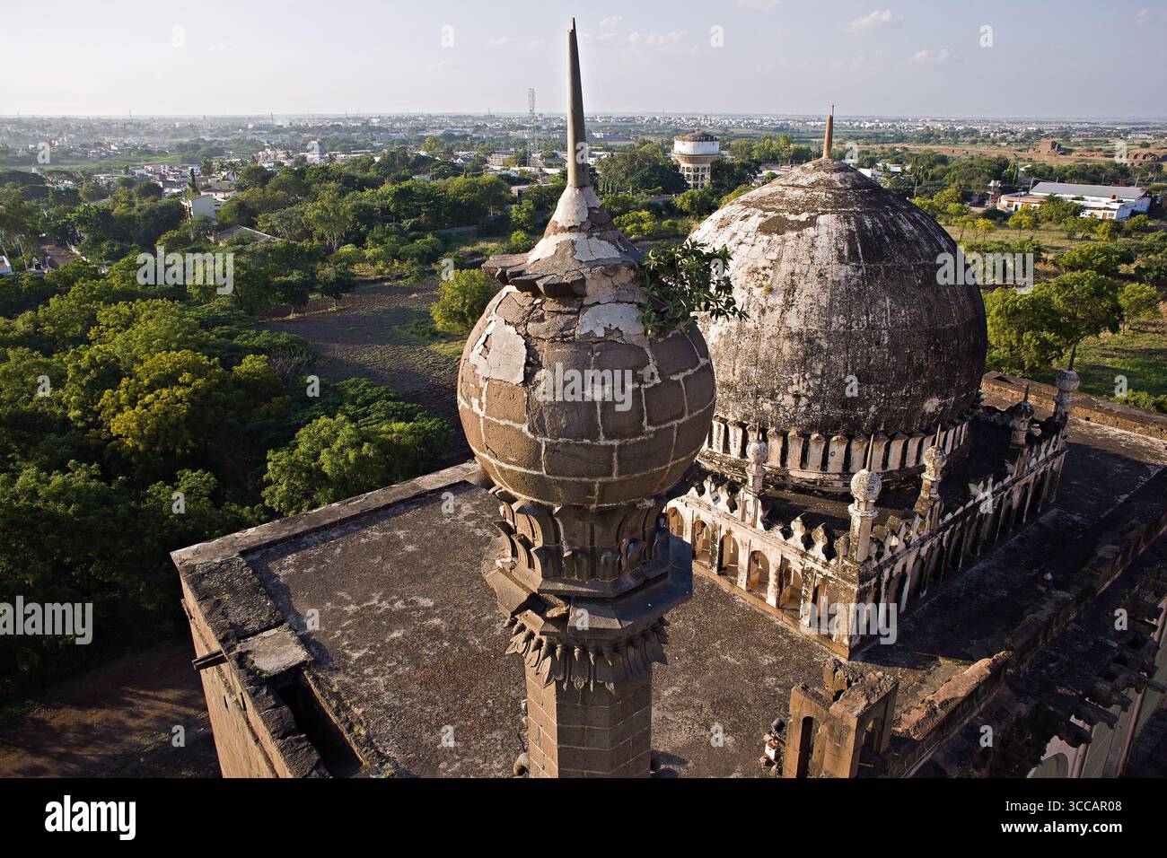 Veduta aerea della cupola e del minareto che si innalzano maestosamente sopra la lussureggiante tettoia della città, un netto contrasto con la proliferazione urbana oltre, Bijapur, Karnataka, India. Foto Stock