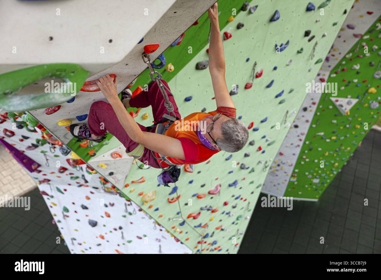 Persona che si arrampica in un punto sopraelevato, avvista l'arrampicata presso l'impianto di arrampicata artificiale della sezione DAV di Mindelheim, stive colorate, Mindelheim, Foto Stock