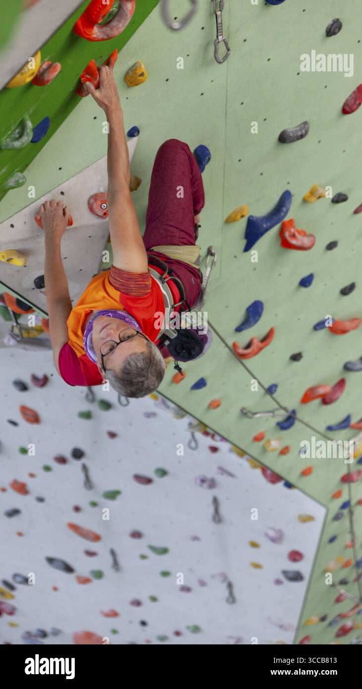 Avvista l'arrampicata presso l'impianto di arrampicata artificiale della sezione DAV Mindelheim, stive colorate, concentrazione sportiva, Mindelheim, Unterallgaeu, Baviera, Ger Foto Stock