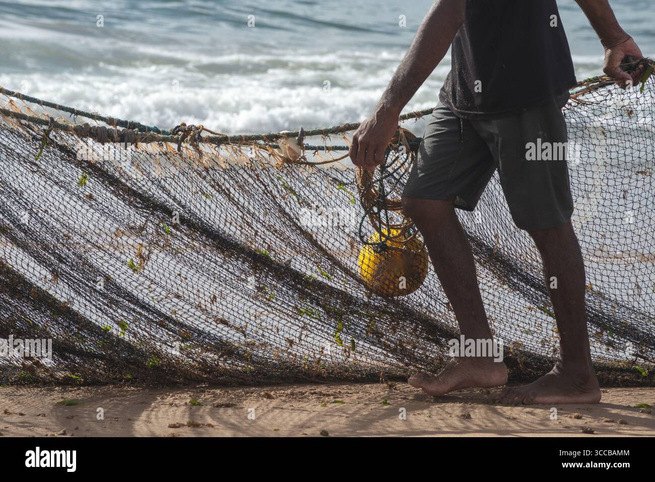 Mezzo corpo di un pescatore non identificato che tira una rete da pesca. specialità di pesce, hobby. Brasile Foto Stock