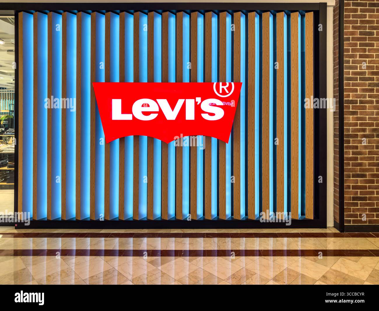 Il grande logo Levi's è esposto su un moderno ripiano retroilluminato con pannelli a righe in un centro commerciale Foto Stock