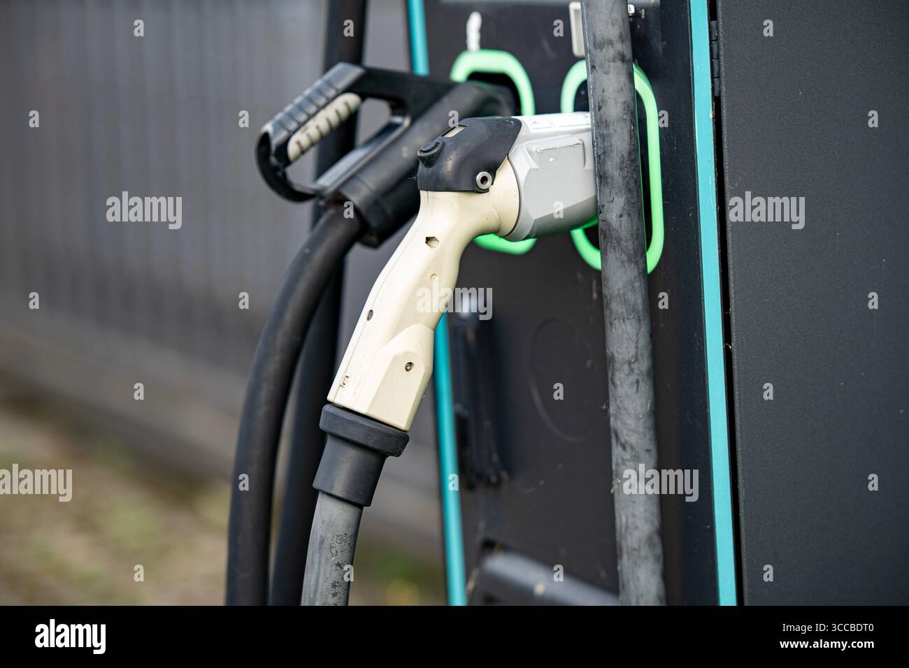 Stazione di ricarica per veicoli elettrici con due connettori: Primo piano dei cavi e delle prese di alimentazione EV moderni con linee LED verdi sul pannello nero Foto Stock
