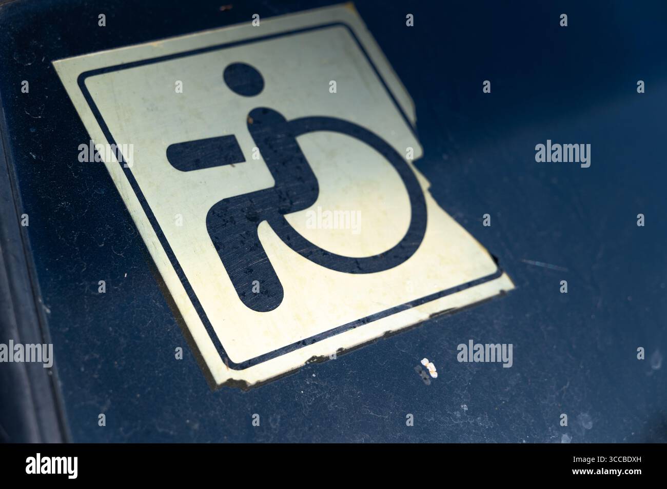 Un'immagine che mostra un simbolo di accessibilità sbiadito della sedia a rotelle sul parabrezza di un'auto, sottolineando l'accesso per disabili. Foto Stock