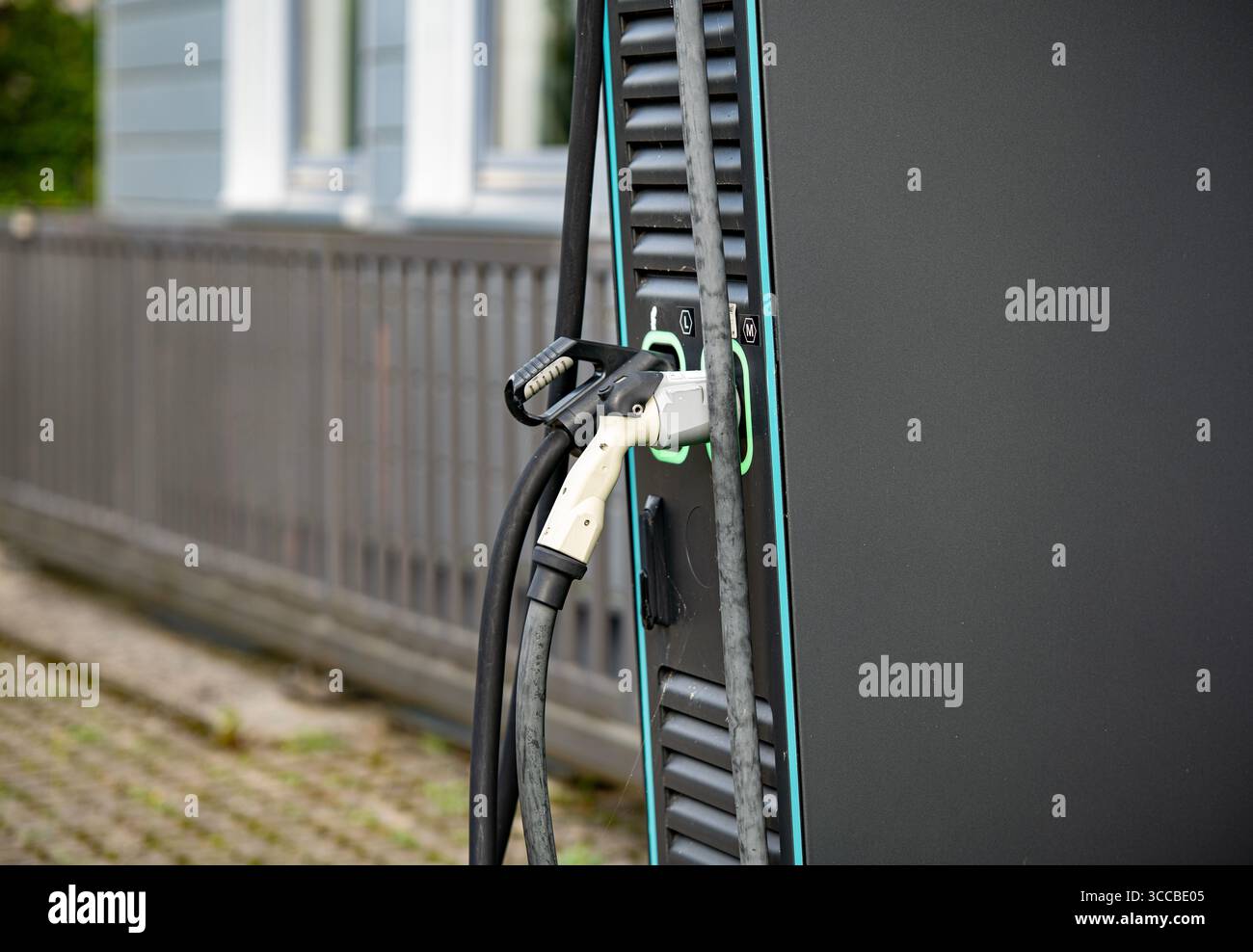 Stazione di ricarica per veicoli elettrici con due connettori: Primo piano dei cavi e delle prese di alimentazione EV moderni con linee LED verdi sul pannello nero Foto Stock