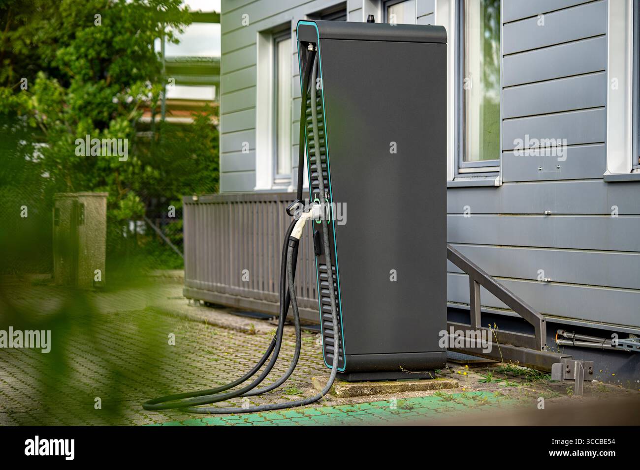 Stazione di ricarica per veicoli elettrici con due connettori: Primo piano dei cavi e delle prese di alimentazione EV moderni con linee LED verdi sul pannello nero Foto Stock