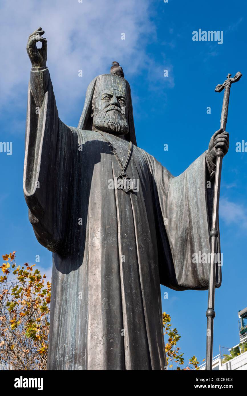 Un piccione seduto in cima alla statua dell'arcivescovo Damaskinos in Piazza Mitropoleos, Atene, Grecia Foto Stock