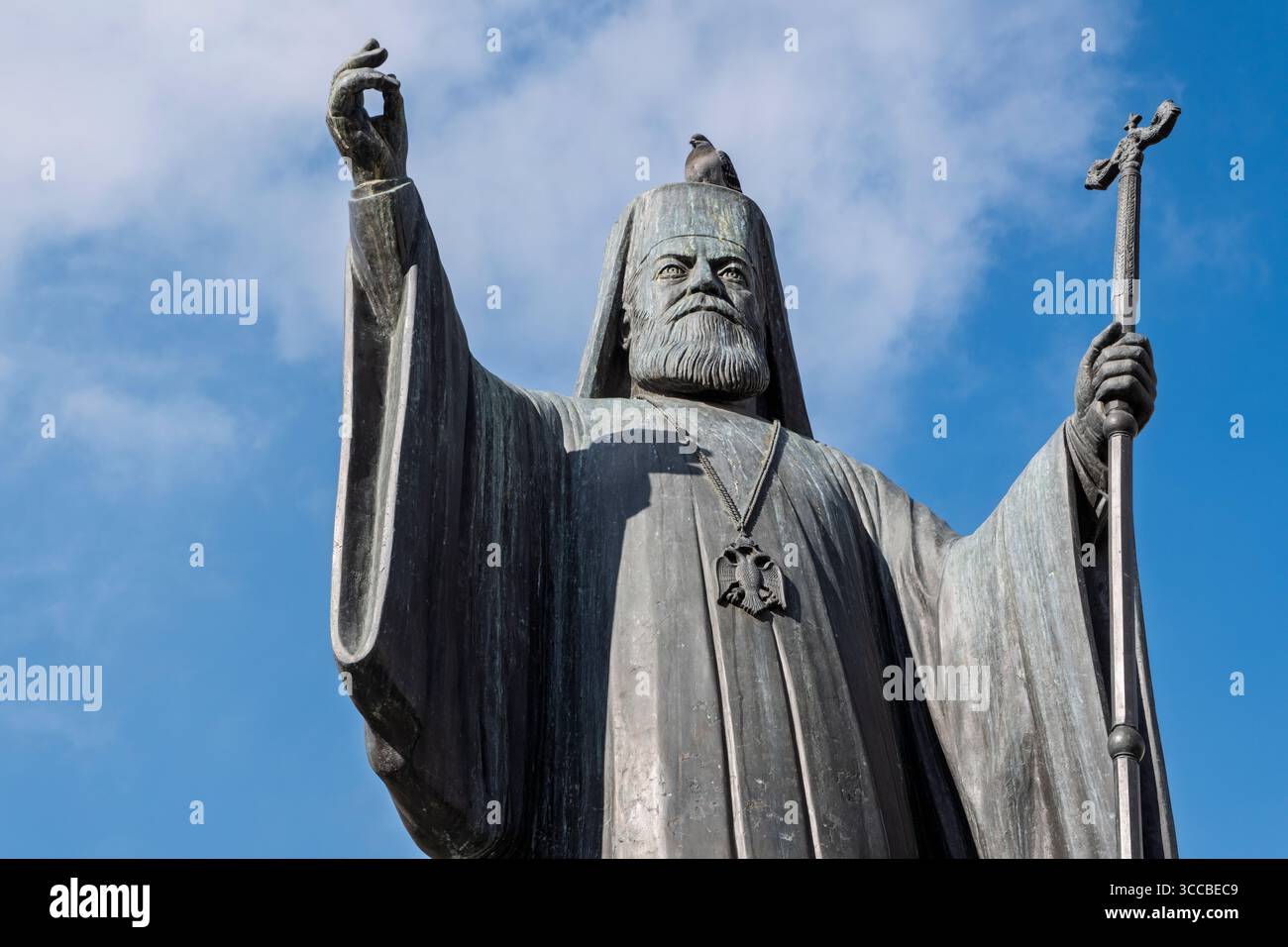 Un piccione seduto in cima alla statua dell'arcivescovo Damaskinos in Piazza Mitropoleos, Atene, Grecia Foto Stock