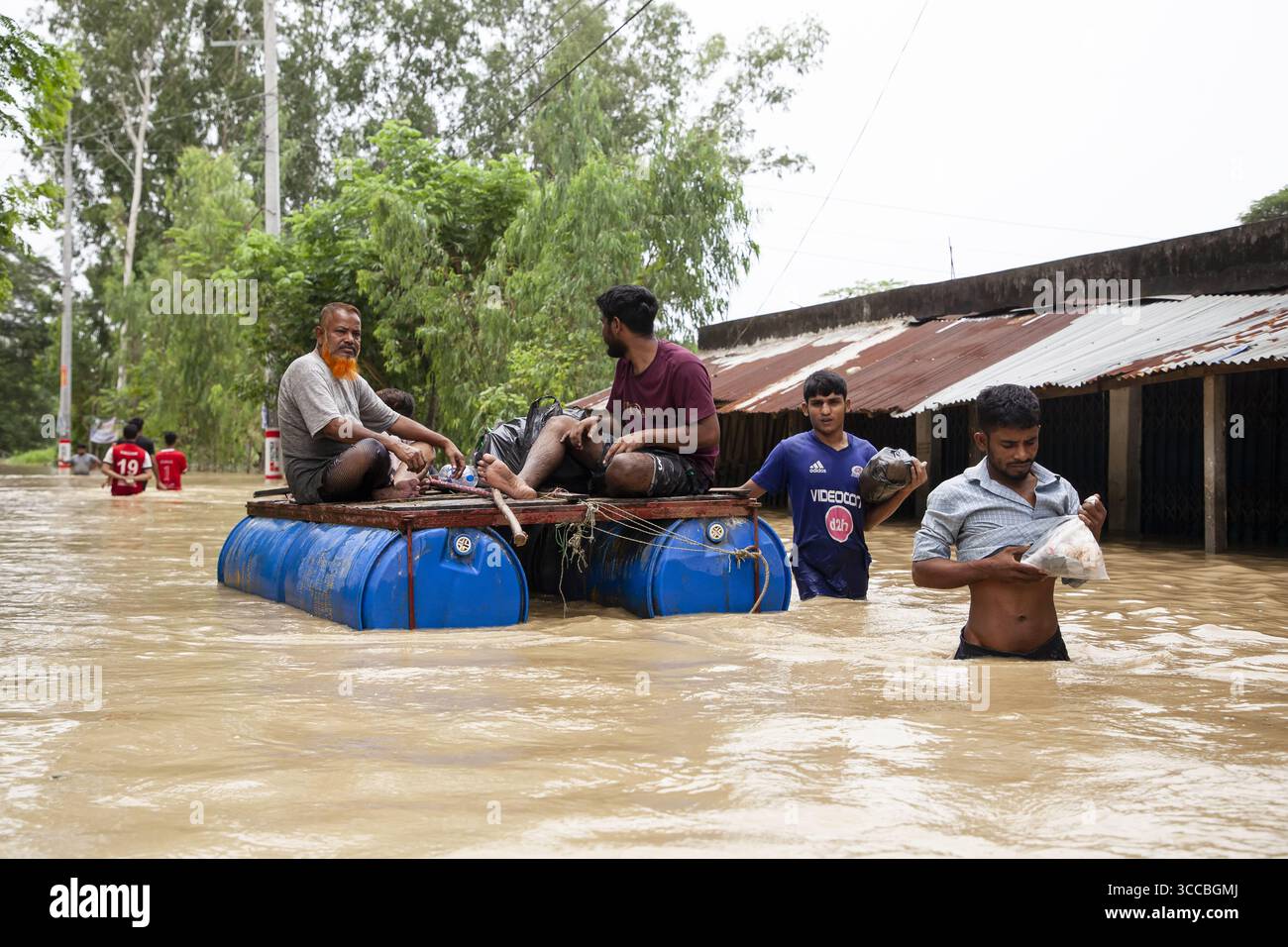 Satkania, Bangladesh - 09 agosto 2023: Vista delle acque alluvionali che travolgono case, con residenti che navigano nelle profondità torbide su zattere improvvisate, una scena di cupa resilienza sotto il cielo coperto. Foto Stock