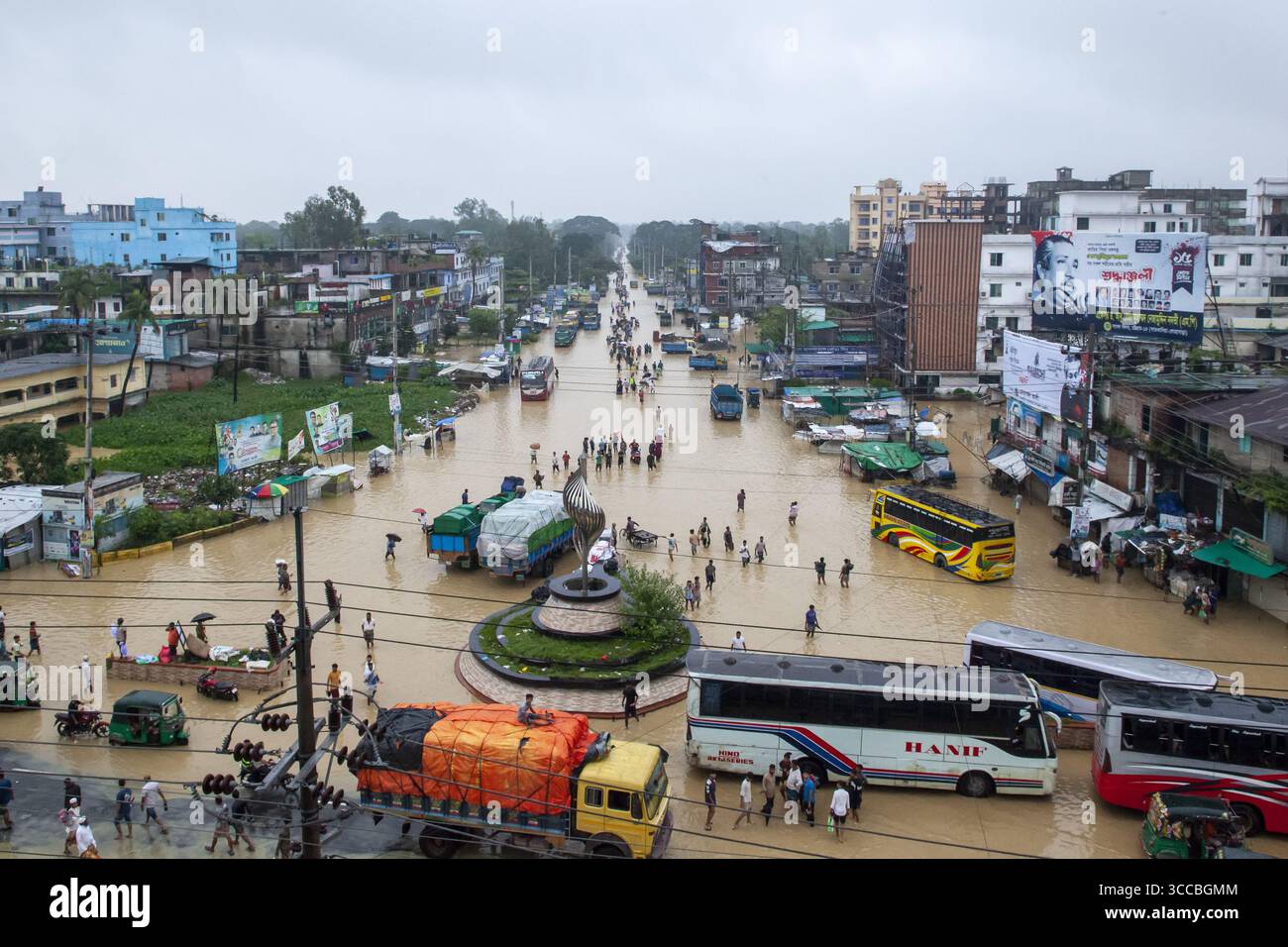 Satkania, Bangladesh - 09 agosto 2023: Vista delle acque alluvionali che inglobano le strade vicino a una rotatoria, che riflette il cielo coperto, mentre i veicoli e il più bello Foto Stock