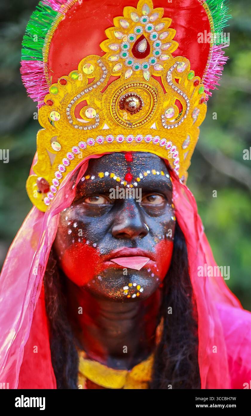 Chandanath Hill, Bangladesh - 12 marzo 2021: Vista di una persona adornata con un vibrante abbigliamento della divinità Kali, con un'impressionante vernice nera per il viso, accenti rossi e un elaborato copricapo dorato. Foto Stock