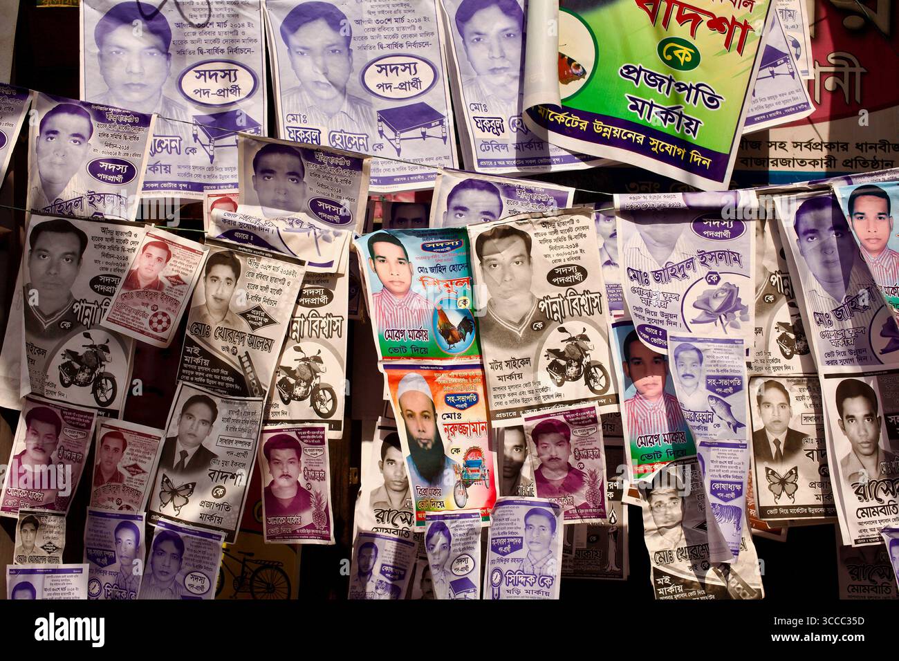 Manifesti elettorali sovrapposti coprono un muro a Bogura, Bangladesh, riflettendo un'intensa campagna politica locale. Foto Stock