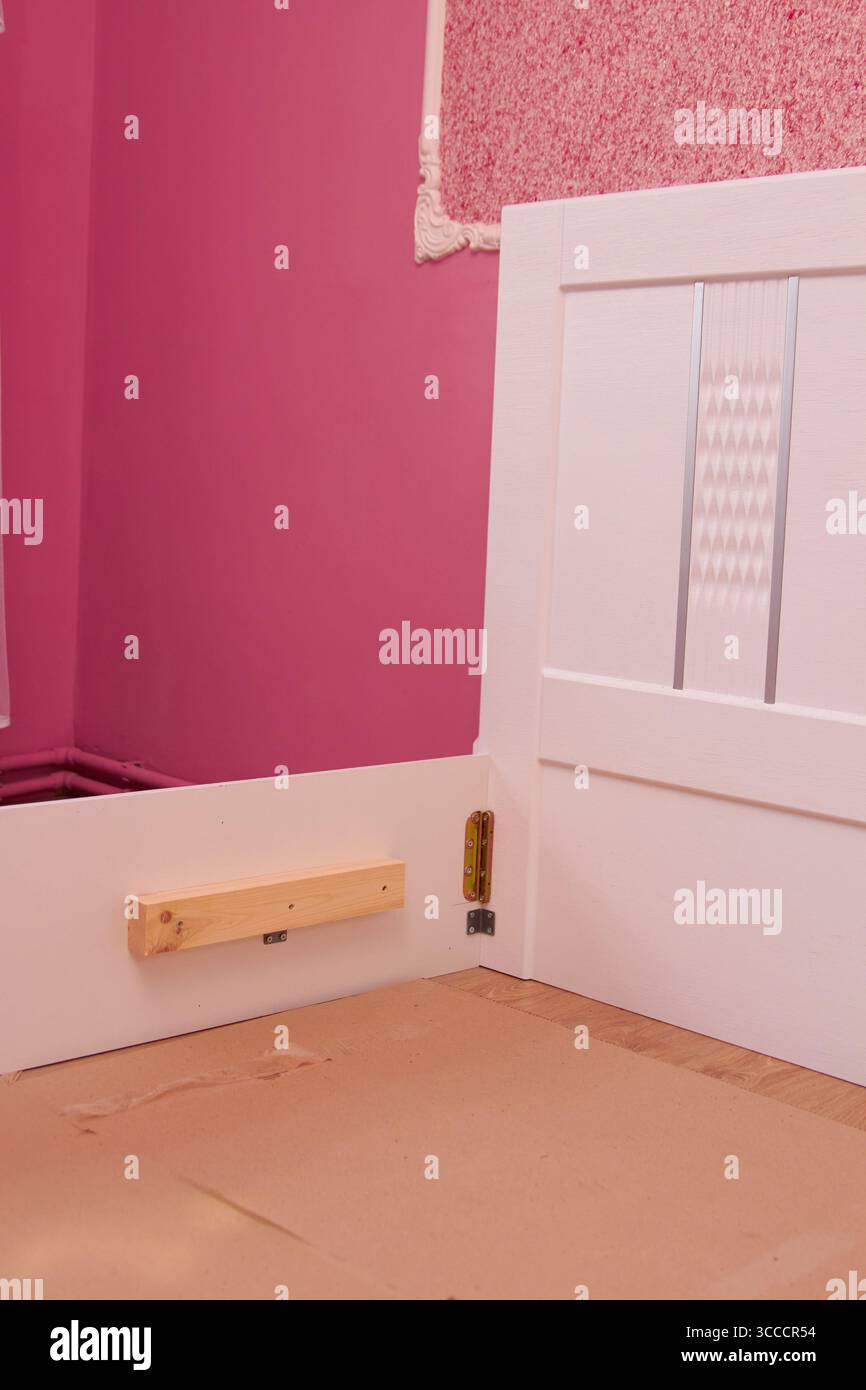 in una stanza rosa che assembla una cornice del letto bianca per una ragazza Foto Stock