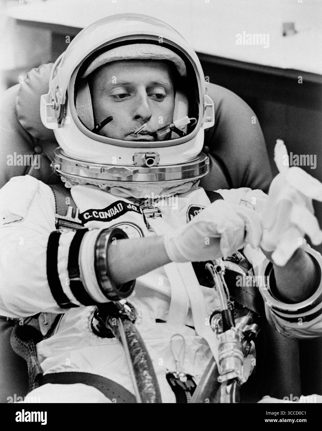 (21 agosto 1965) --- l'astronauta Charles Conrad Jr. Tira un paio di guanti bianchi e la sua temperatura viene presa durante le operazioni di suiting la mattina del decollo del volo spaziale Gemini-5 da Cape Kennedy, Florida. Foto Stock